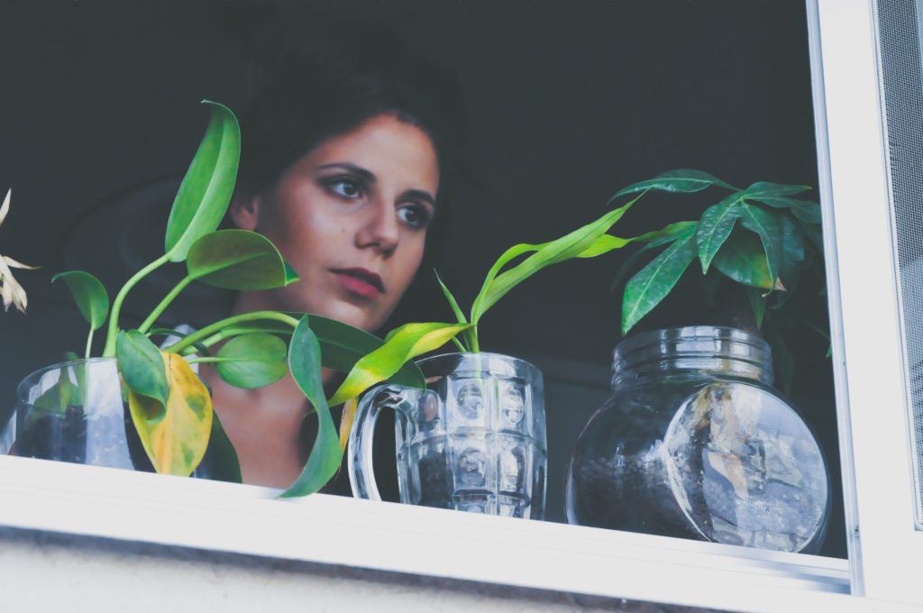 Women looking out a window with small plants on her window sill